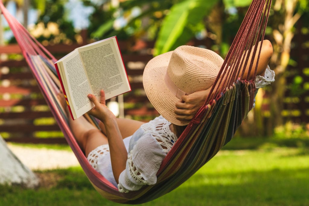 femme entrain de lire un livre dans son hammack, dans son jardin